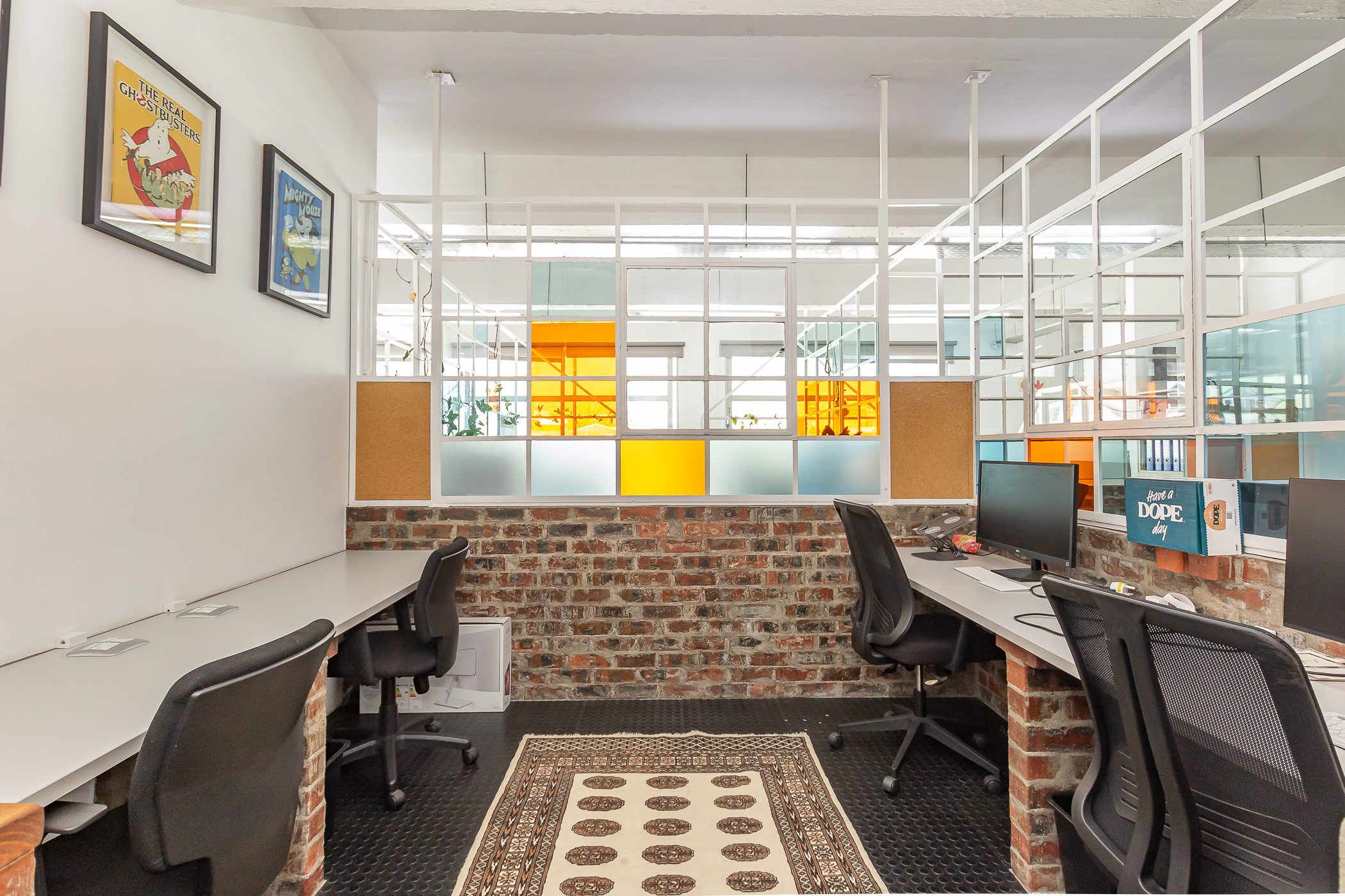 Coworking desk pod for four with exposed brick and coloured glass partition at Cape Town Office