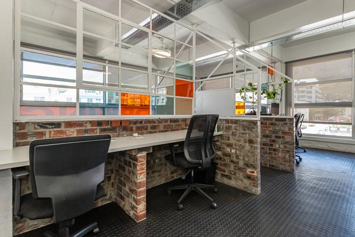 Coworking desk pods with exposed brick at Cape Town Office