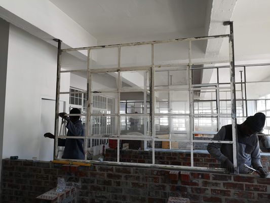 Builders fitting steel window frames, November 2018